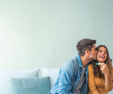 Photograph of happy, loving couple holding pregnancy test.