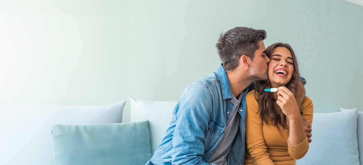 Photograph of happy, loving couple holding pregnancy test.